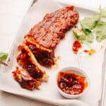 Spicy Sticky ribs on a plate with extra sauce.