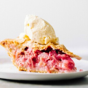 A slice of strawberry rhubarb pie with ice cream.