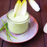 Homemade Green Goddess dressing in a jar with vegetables.