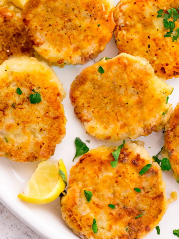Fish cakes with potato on a plate with parsley and lemon.