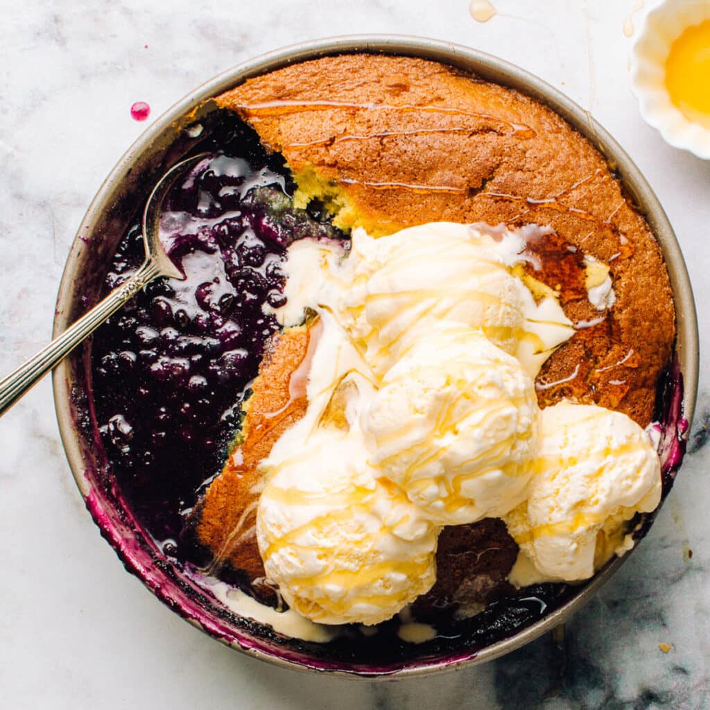 Blueberry pudding cake in a cake pan with ice cream.