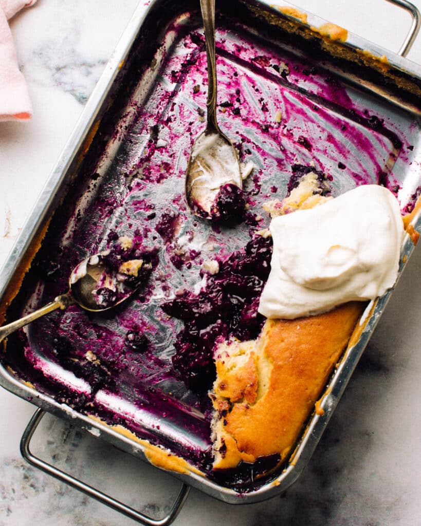 Blueberry pudding cake in a pan with spoons.