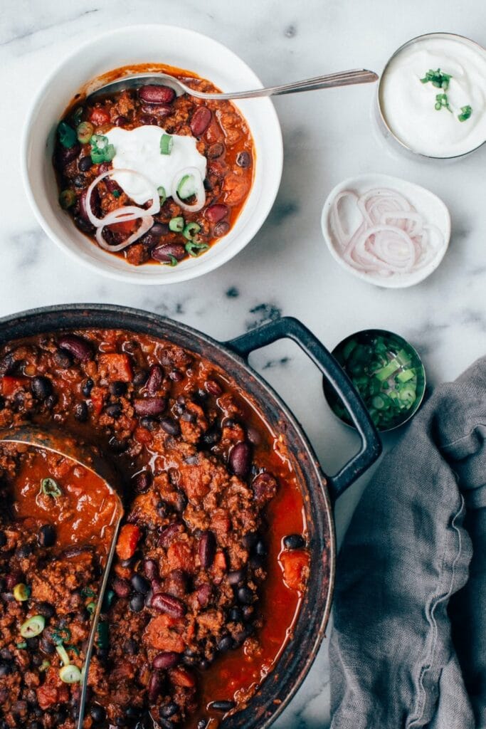 Dutch oven with chili con carne and a bowl by side