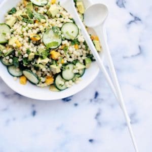Israeli couscous salad on a plate with spoons