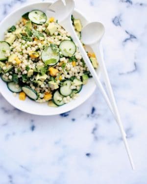 Israeli couscous salad on a plate with spoons