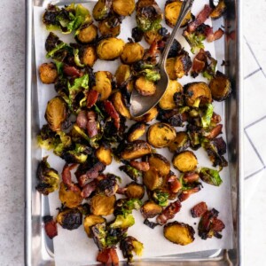 Crispy Roasted Brussels Sprouts with Maple and Bacon on a baking sheet with parchment paper.