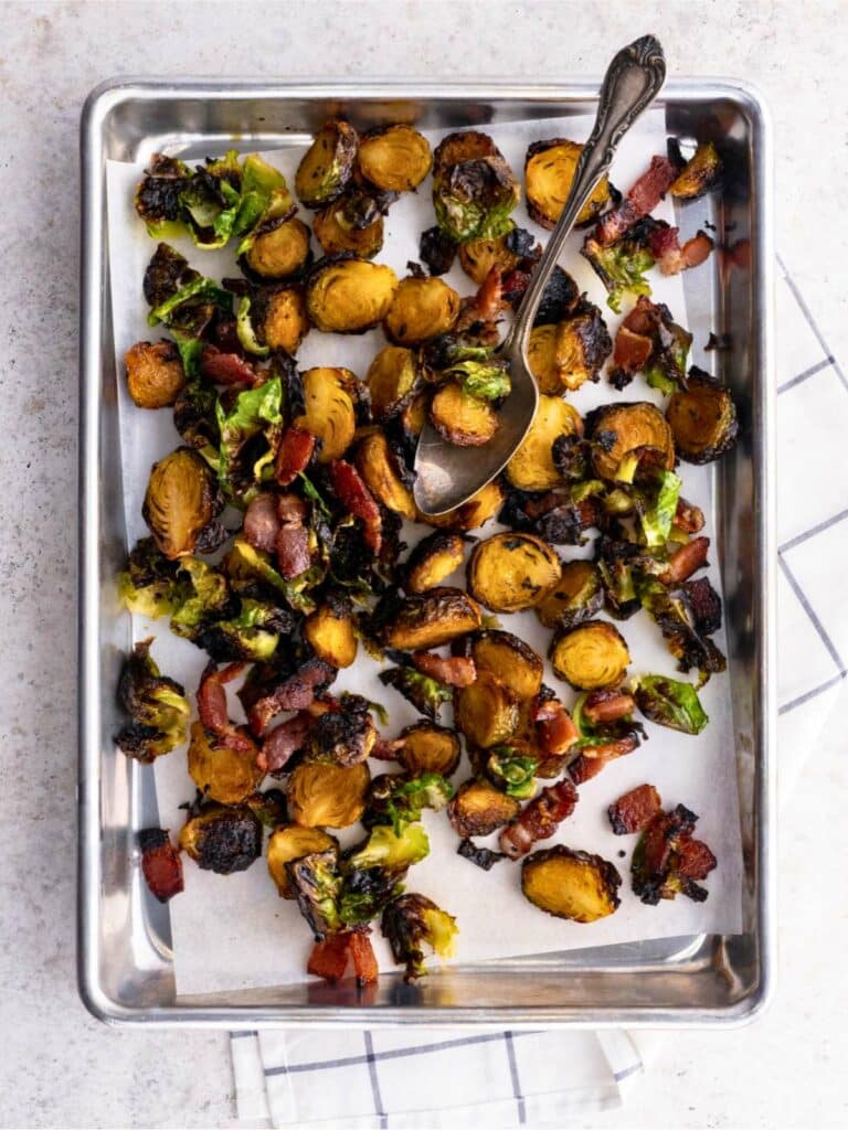 Crispy Roasted Brussels Sprouts with Maple and Bacon on a baking sheet with parchment paper.