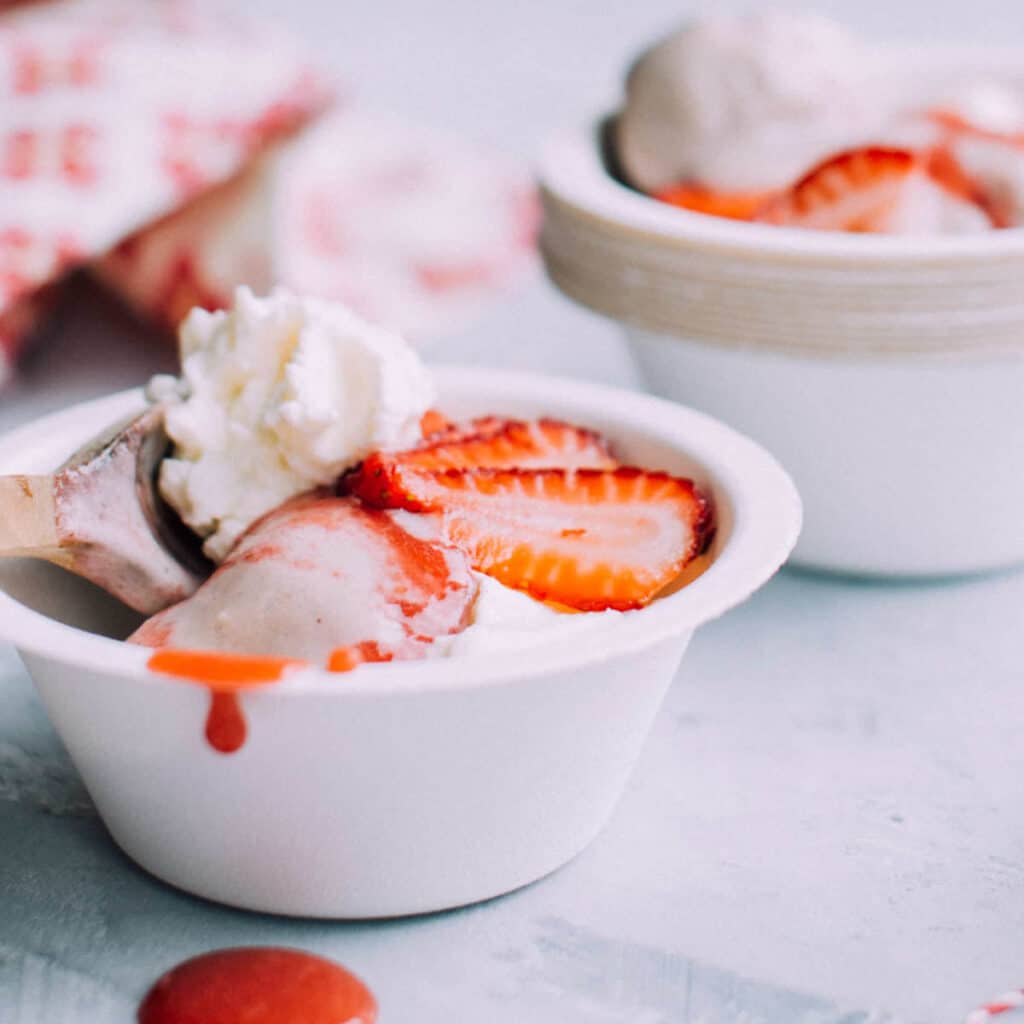 banana ice cream in a bowl topped with strawberries.