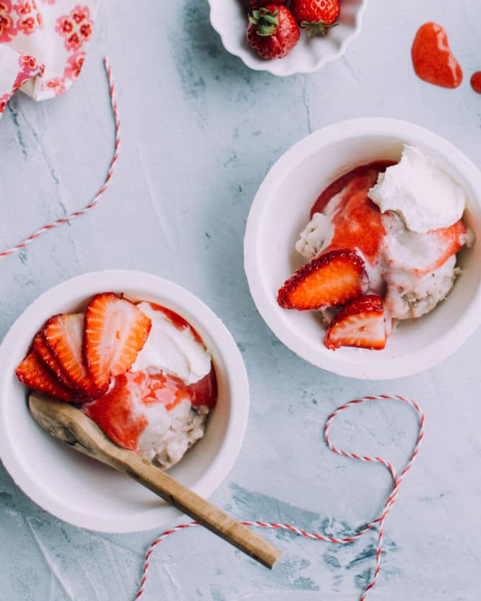 close up of banana ice cream in white bowls with strawberries on top