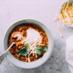Instant Pot Chicken Chili in a bowl with sour cream and cilantro.