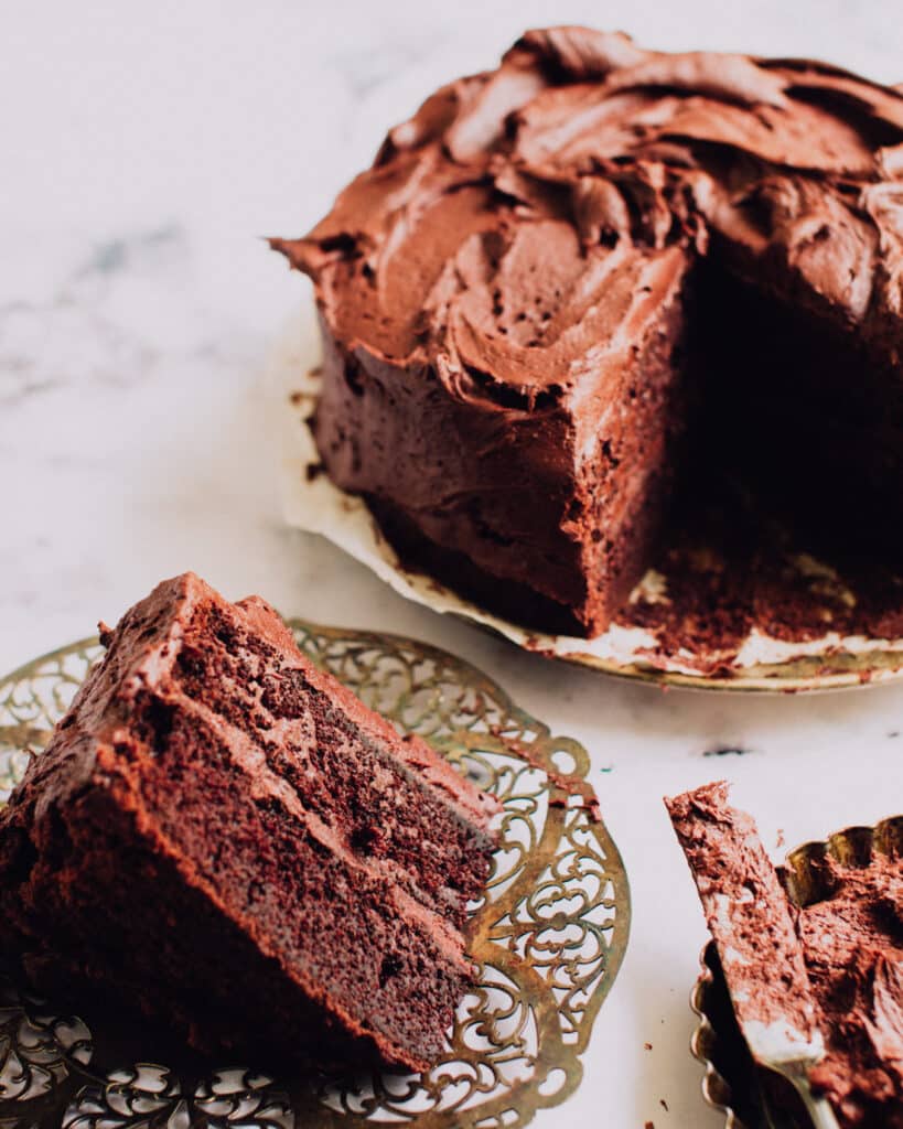 A Slice of moist chocolate cake next to the whole cake.