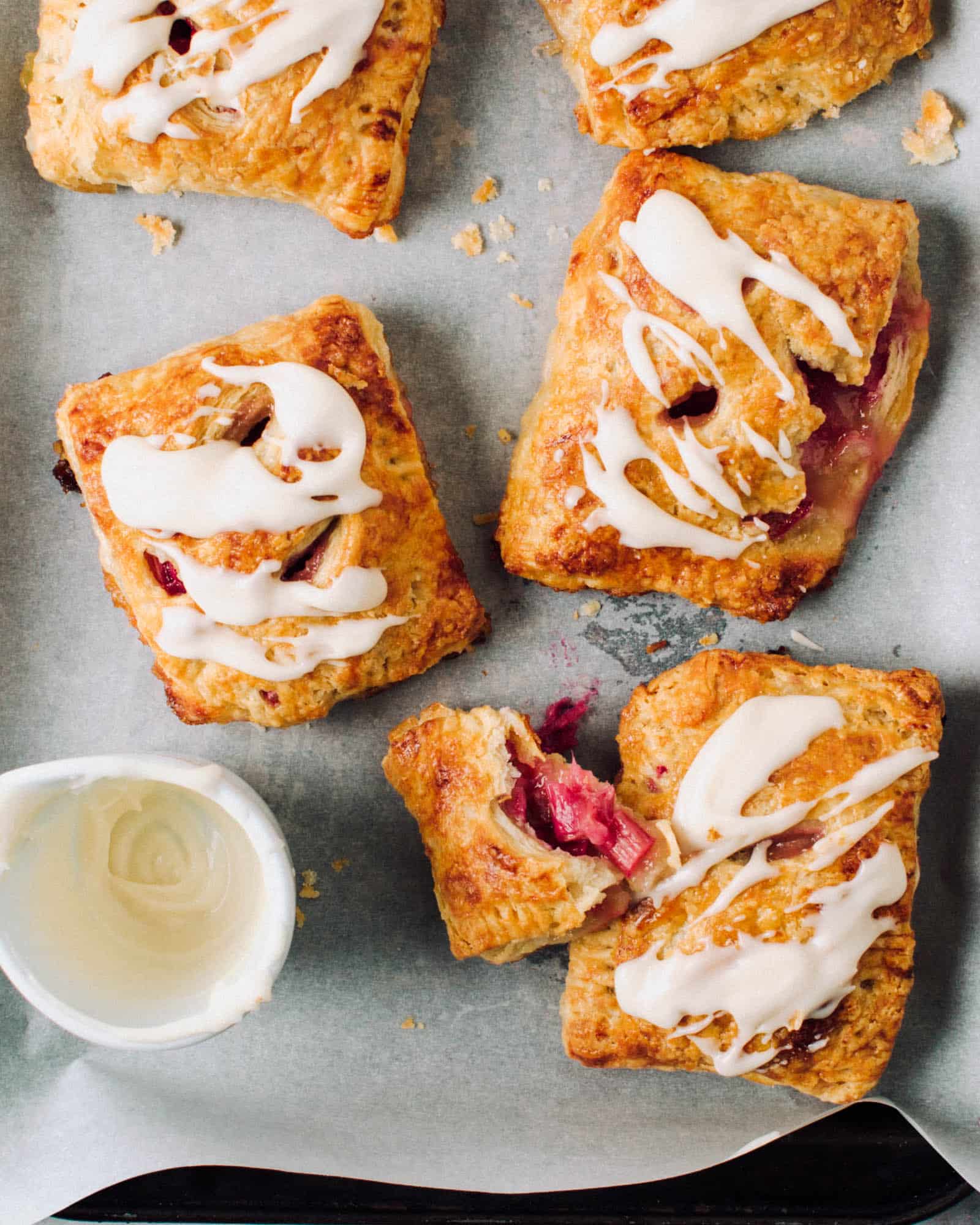 Rhubarb hand pies with icing on a tray.