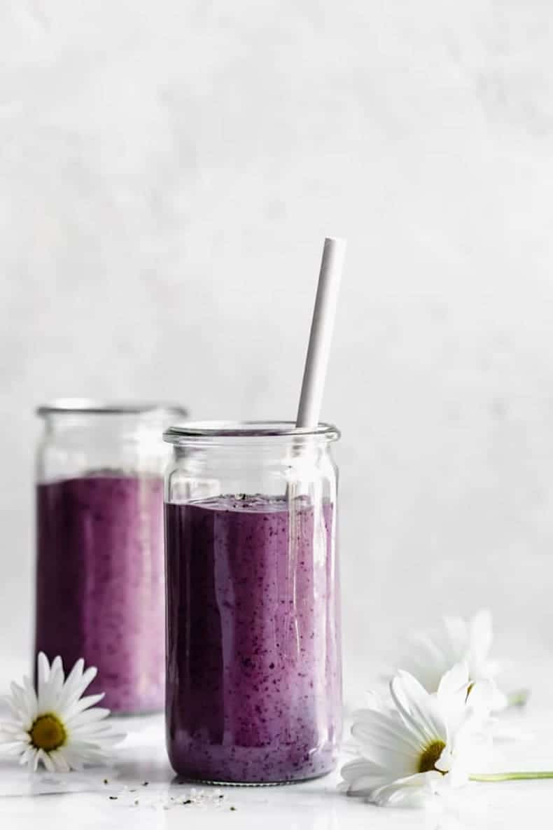 blueberry smoothie on marble backdrop with daisy on table