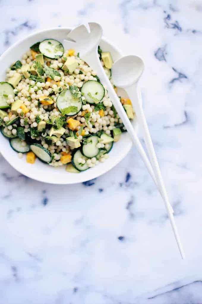 Israeli couscous salad with cucumbers and avocado on a plate.