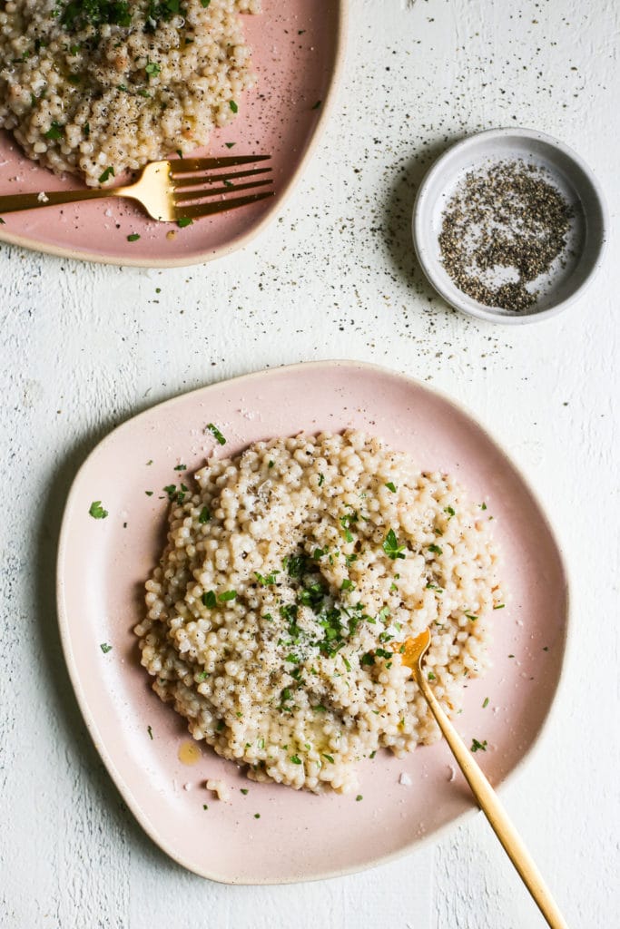 Creamy Israeli couscous with pepper and herbs on a plate.