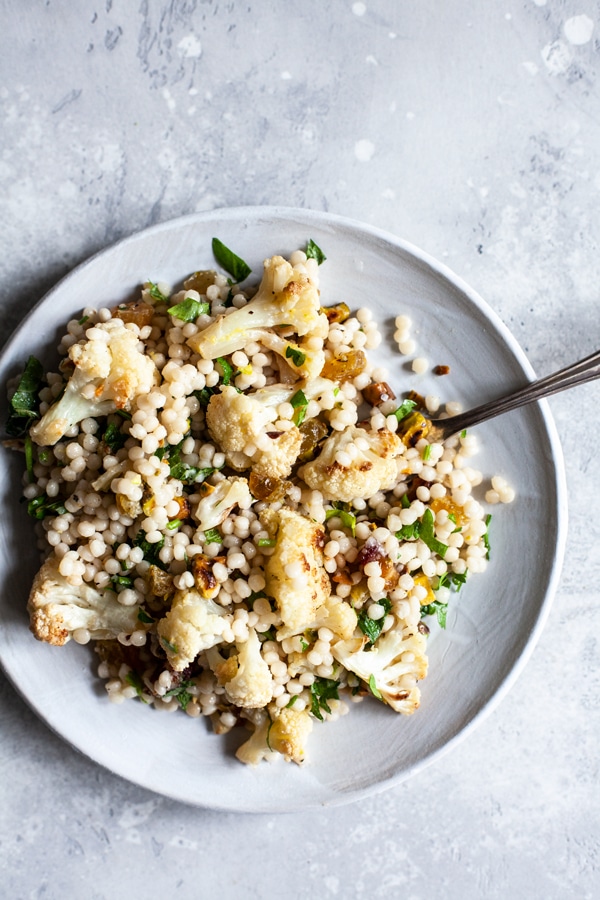 Israeli couscous salad with cauliflower and raisins on a plate.
