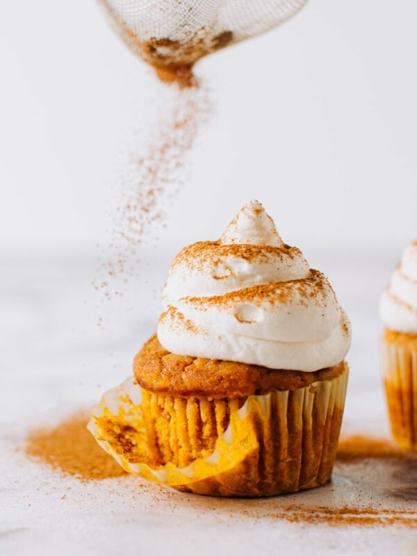 Pumpkin cupcake being dusted with cinnamon.