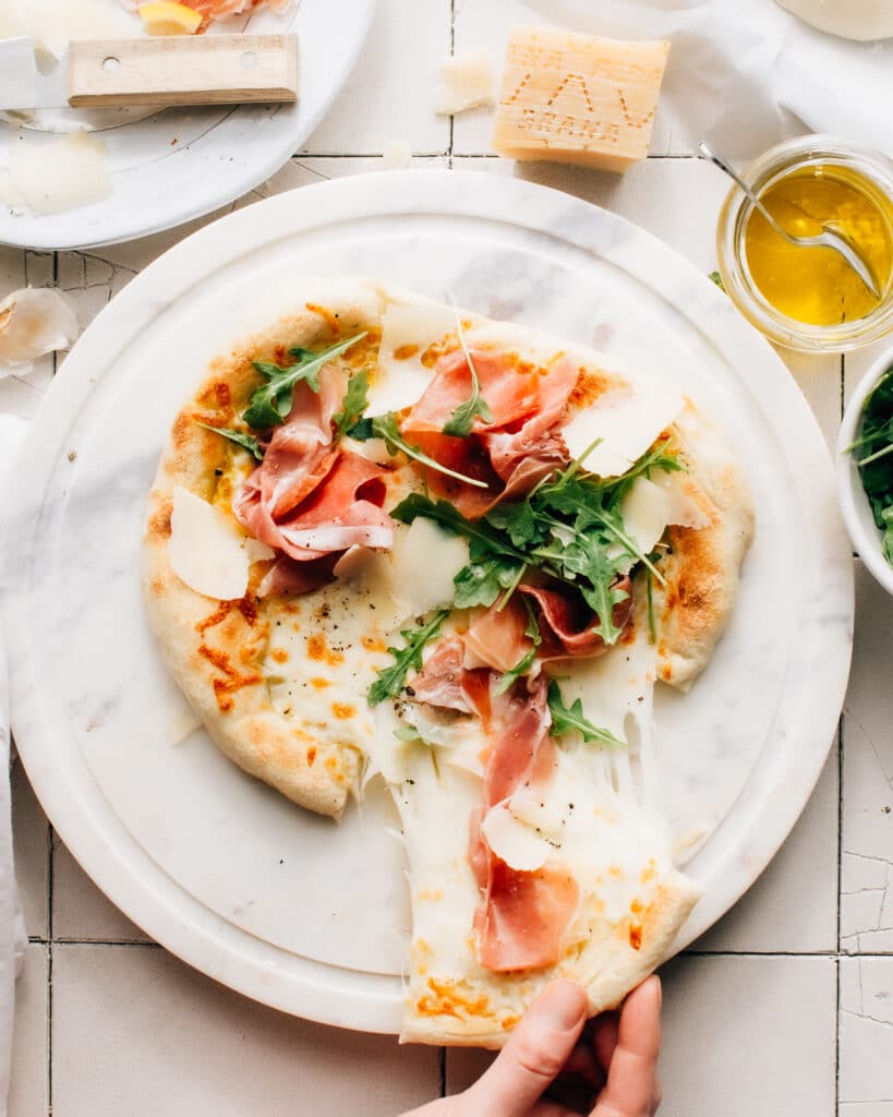 Prosciutto Pizza with Arugula is super easy to whip up, with olive oil and garlic in lieu of a sauce. It is layered with texture and flavour.