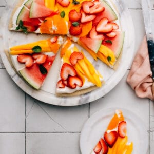 This Fruit Pizza recipe has the best, fluffy cream cheese frosting and an easy sugar cookie base.  You can make fun, beautiful fruit designs into Easter eggs, a patriotic flag for Memorial Day or Canada Day, or any holiday.