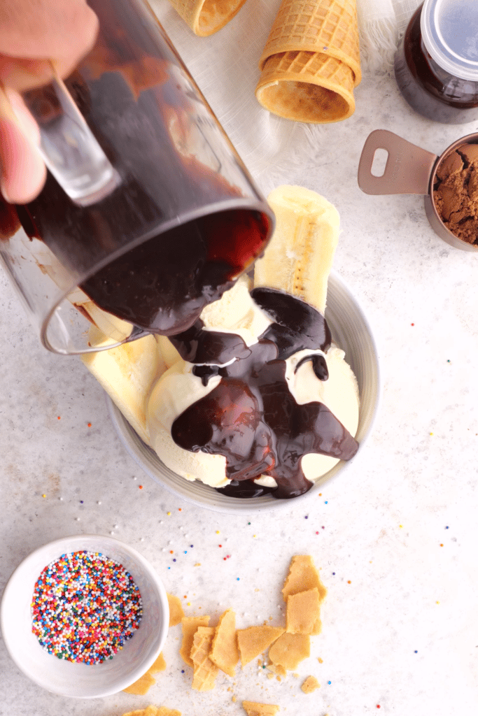 chocolate hot fudge being poured on vanilla ice cream