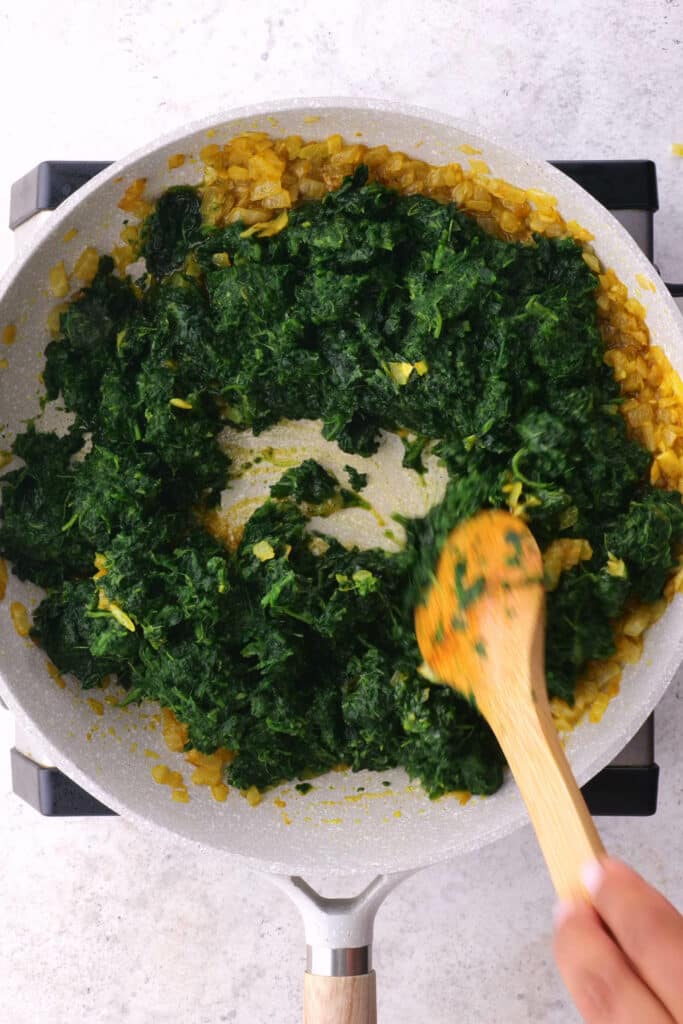 Stirring spinach into saag paneer.