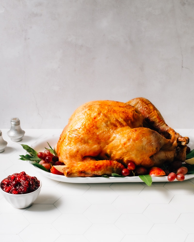 Roast turkey on a serving platter with cranberry sauce.
