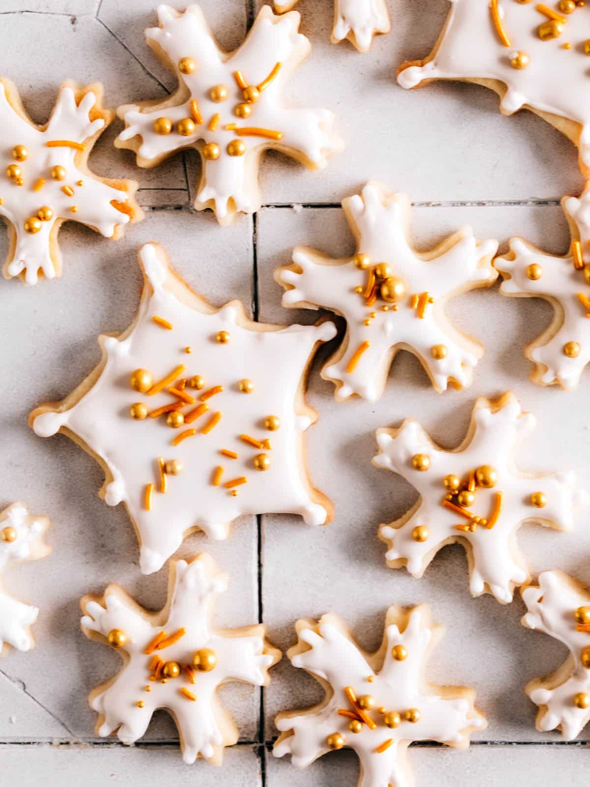 Snowflake cookies with royal icing and sprinkles on a table.