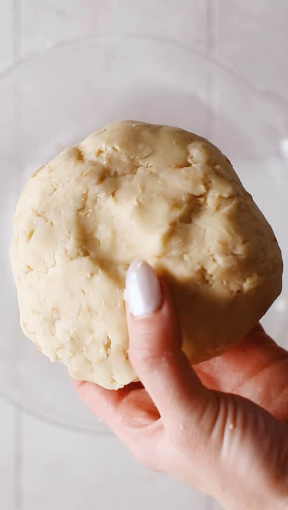 Holding a ball of kourabiedes dough.