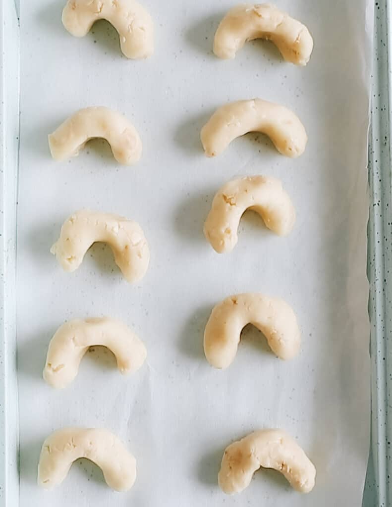 Unbaked kourabiedes on a baking sheet.
