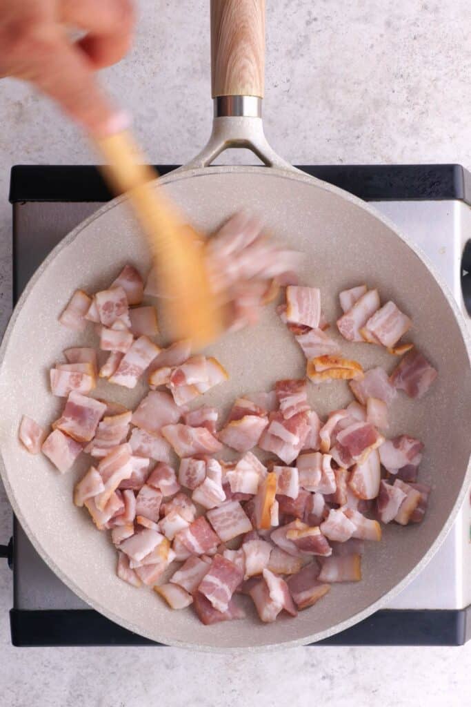 Partially cook the bacon in a frying pan.