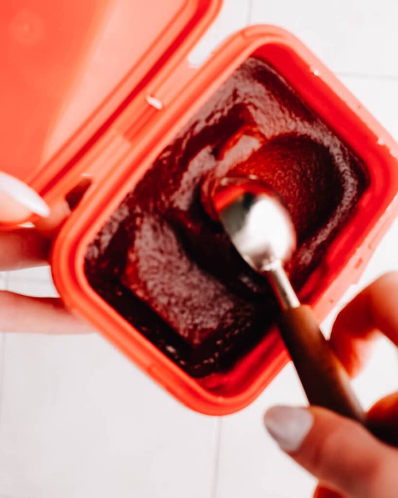 Taking a scoop of gochujang from the container.