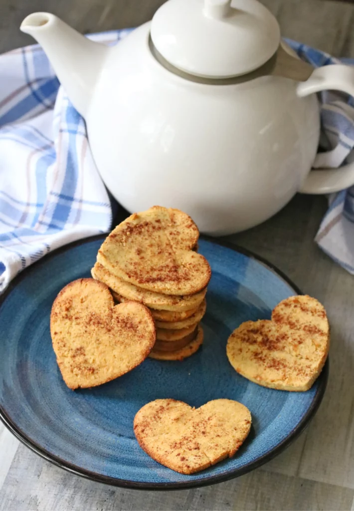 cinnamon sugar cookies stacked on a plate with tea pot