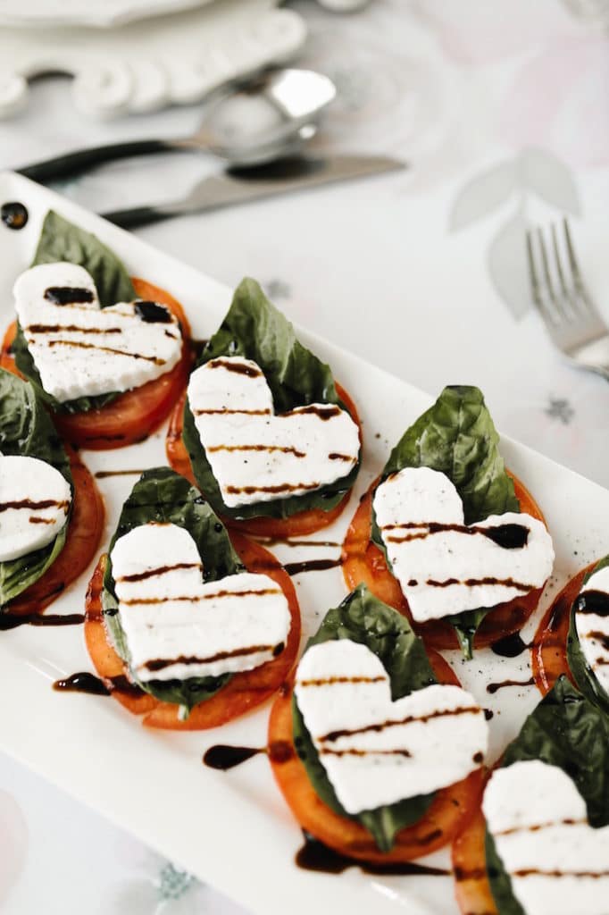 A plate of Heart-shaped Caprese Salad, made with fresh tomatoes, mozzarella, and basil.