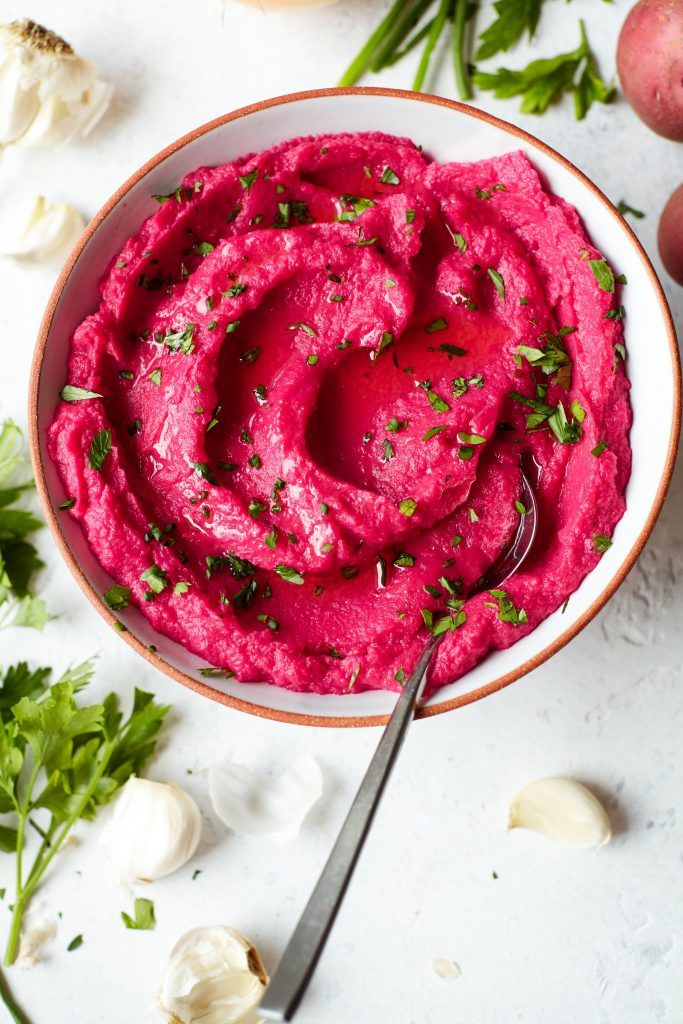A ceramic bowl of Beet Mashed Potatoes topped with fresh cilantro
