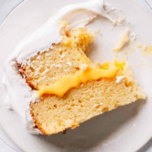 A slice of lemon curd cake on a plate with a bite taken out.