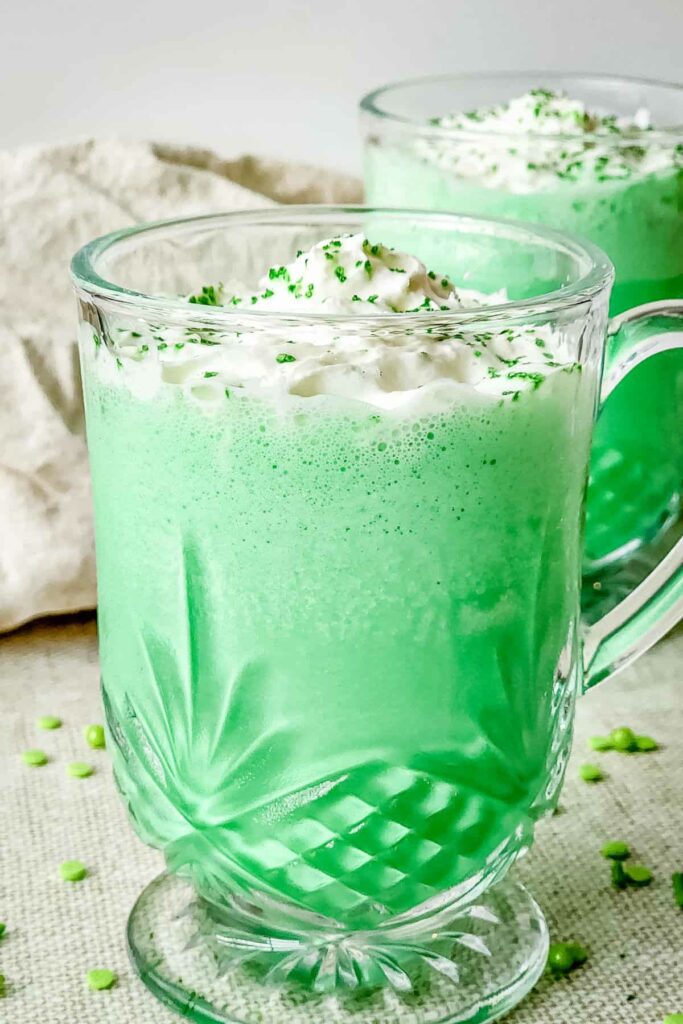A glass of copycat Shamrock Shake with bright green hue and whipped cream on top