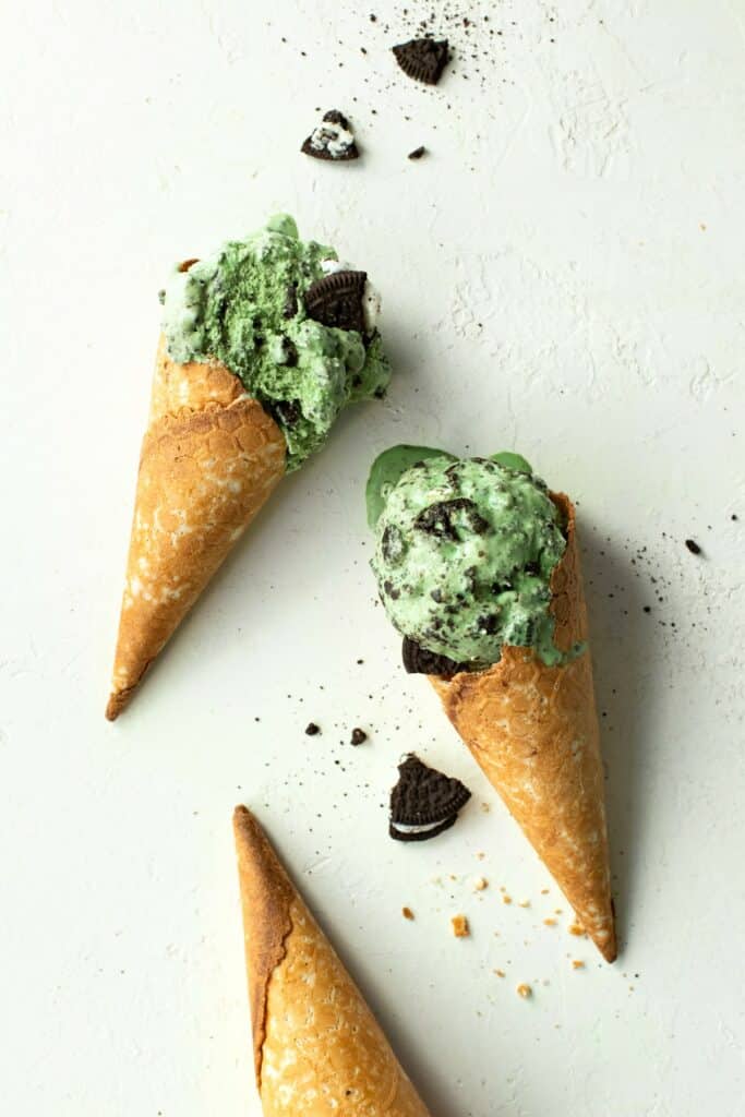 Two cone waffles topped with fresh mint Oreo ice cream. The cones have a golden-brown color and a crisp texture, while the ice cream is creamy and indulgent, dotted with chunks of Oreo cookies.