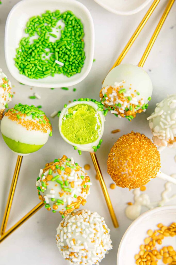 Green cake pops on golden sticks with a cake center, decorated with white chocolate and green sprinkles