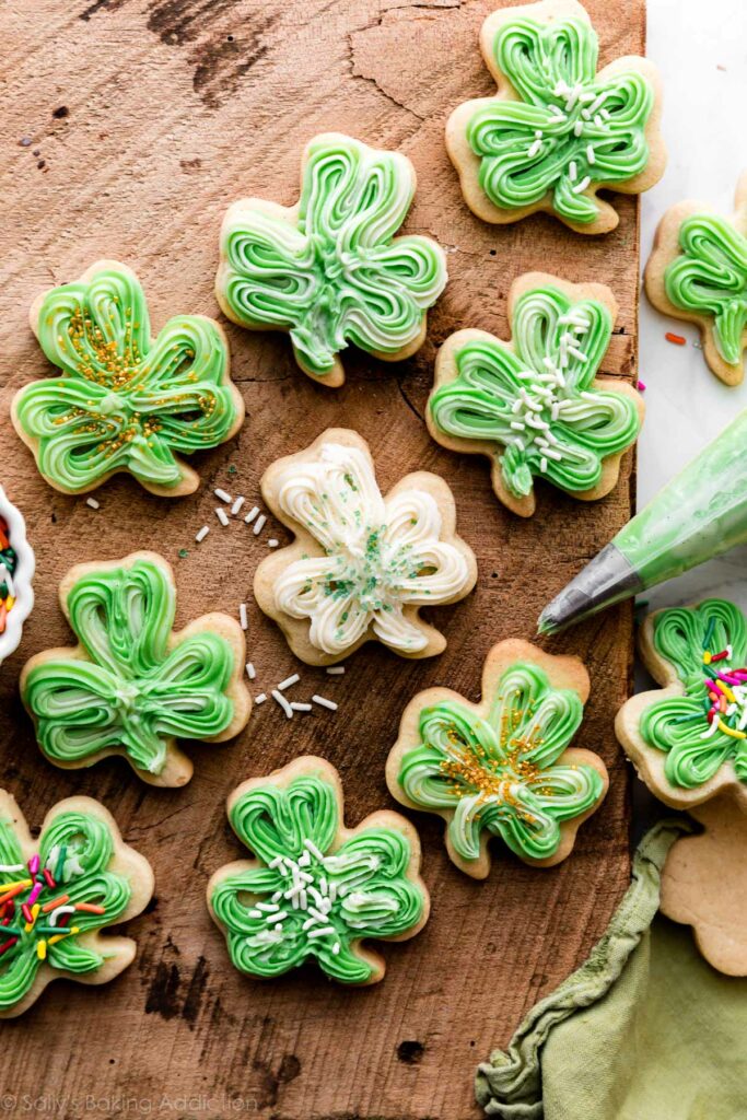 Shamrock-shaped vanilla bean St. Patrick's Day sugar cookies on a brown wooden surface
