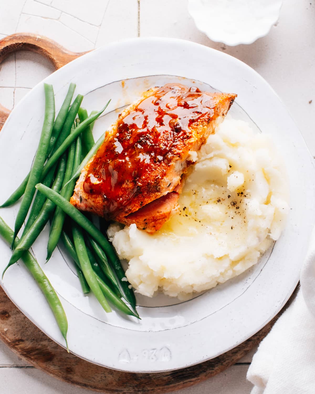 Cajun Honey Butter Salmon served over a fluffy mound of mashed potatoes and beans, topped with a drizzle of the honey sauce.