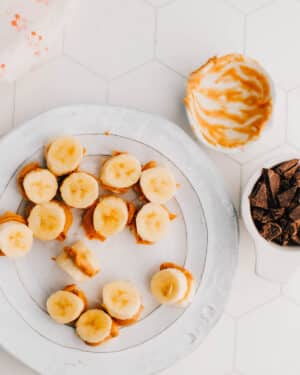 Assembling peanut butter banana bites on a plate.