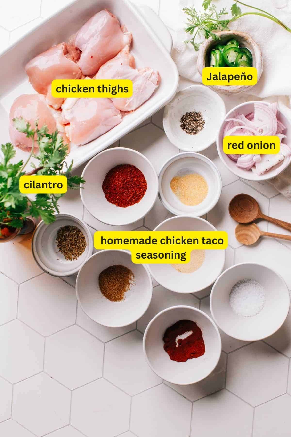 Ingredients for chicken street tacos on a kitchen countertop including chicken thighs, jalapeno, red onion, cilantro and homemade chicken taco seasoning.