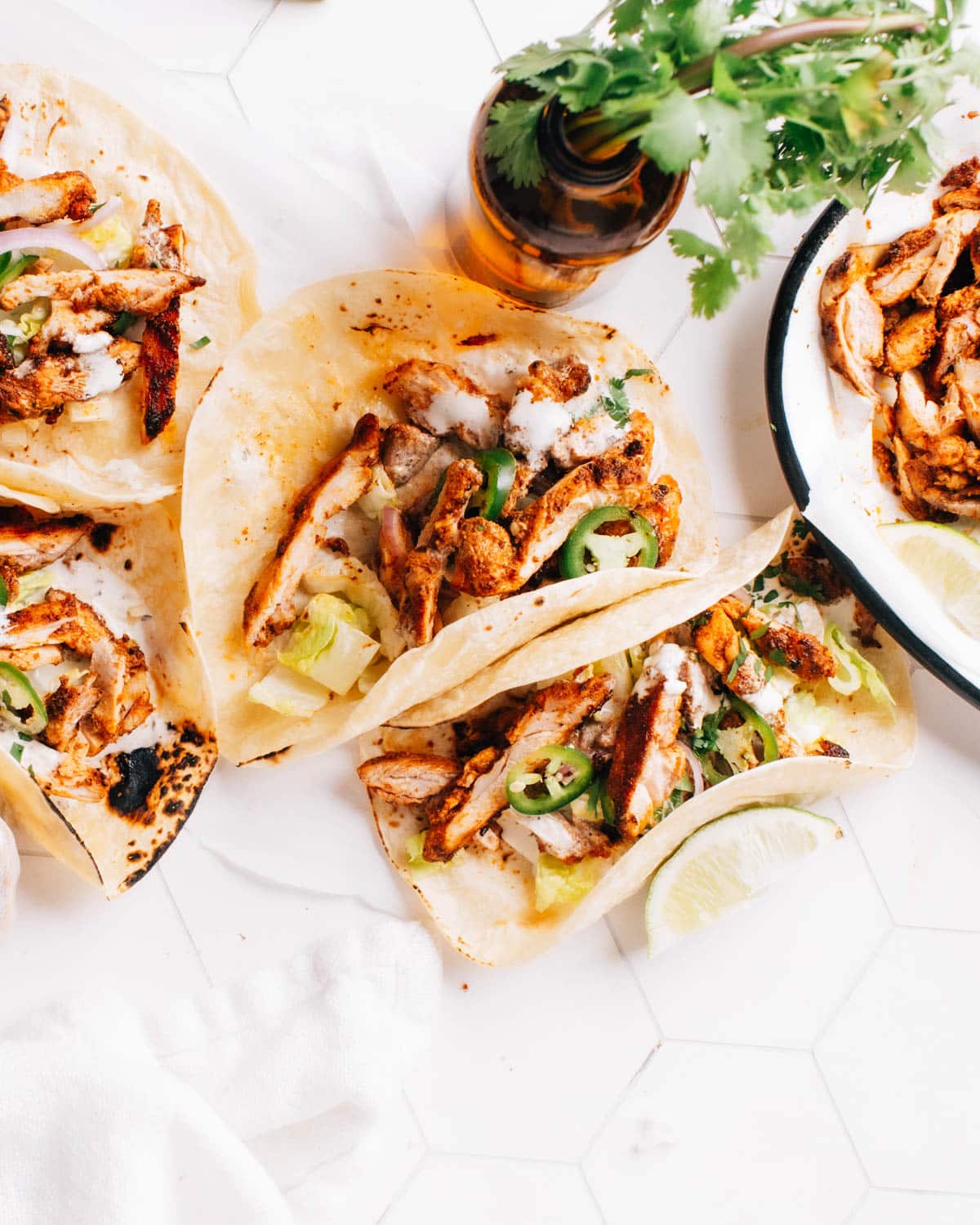 Ready-to-eat chicken street tacos topped with a dollop of cilantro lime crema and garnished with sliced onions and jalapeno.