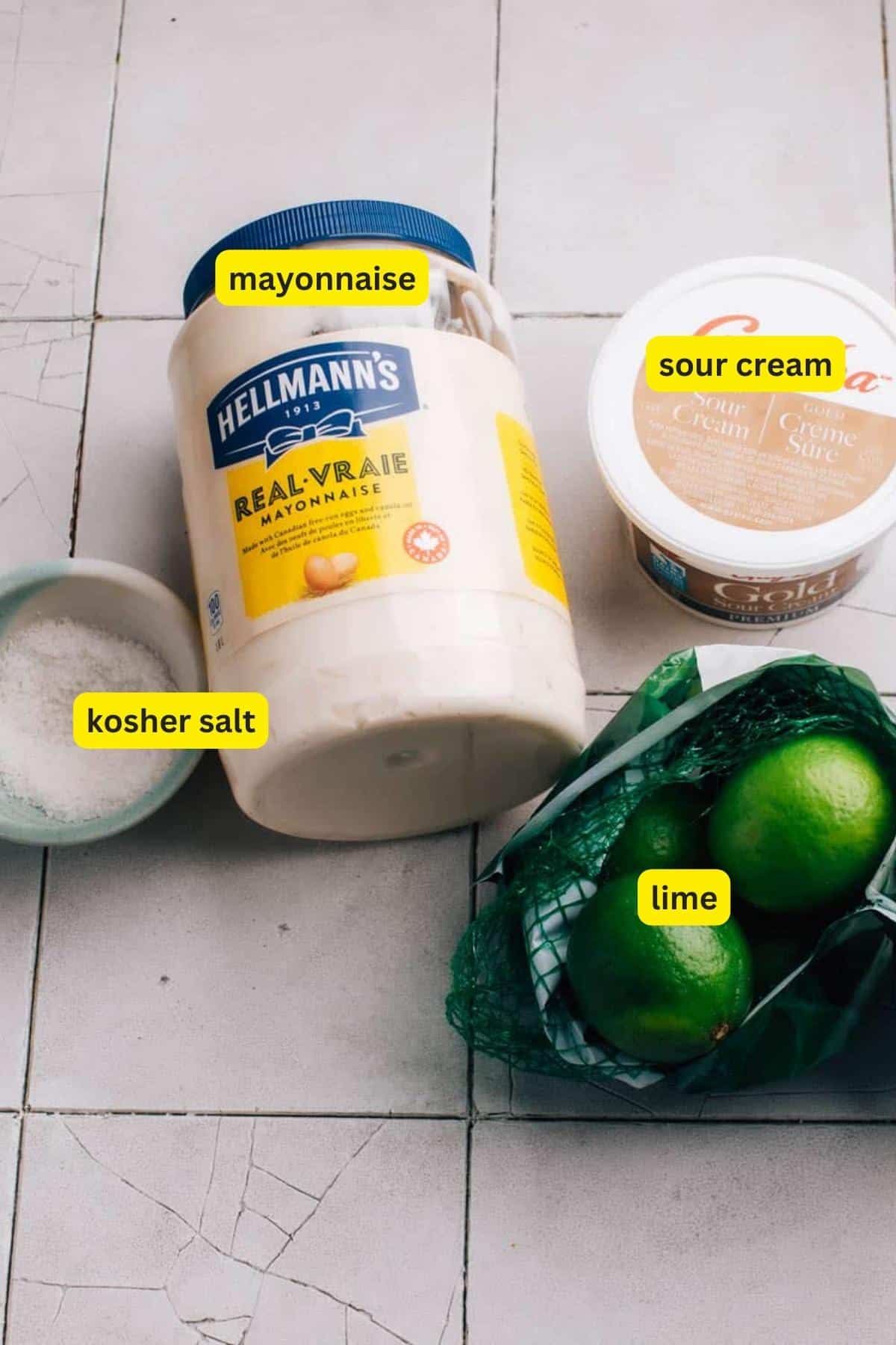 Ingredients for Cilantro Lime Cream placed on a kitchen countertop including mayonnaise, sour cream, kosher salt and lime.