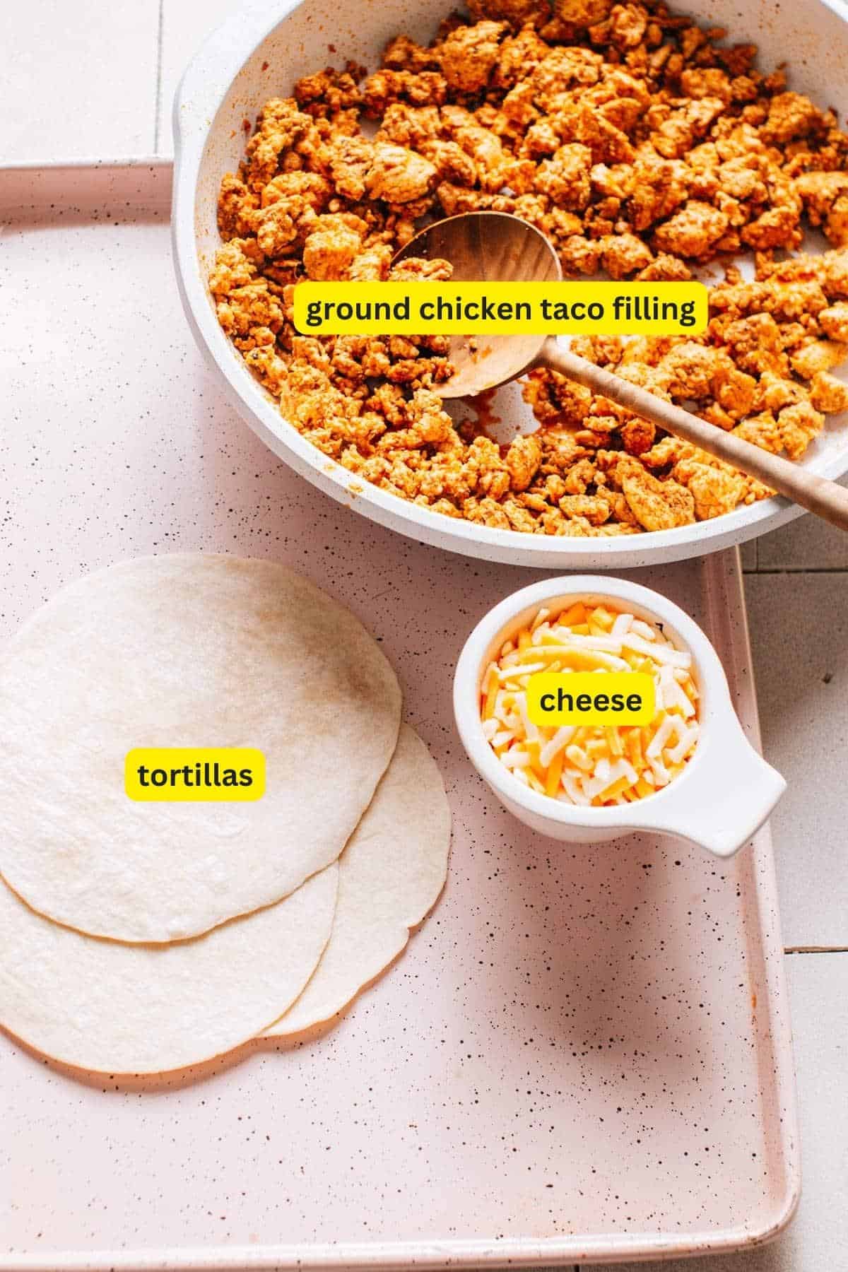 Ingredients for crispy baked chicken tacos, includes ground chicken taco filling, tortillas and cheese.