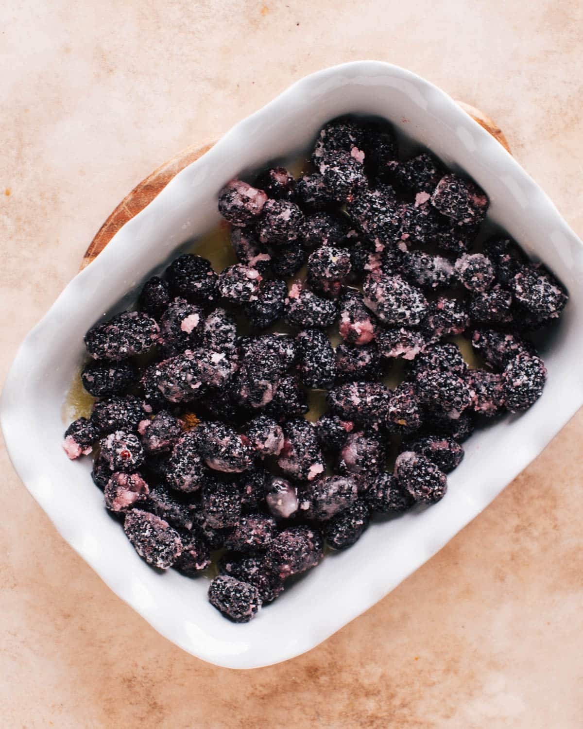 A white baking dish filled with freshly made blackberry filling to make blackberry cobbler.