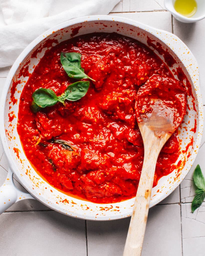 Red sauce for pizza in a skillet with basil.