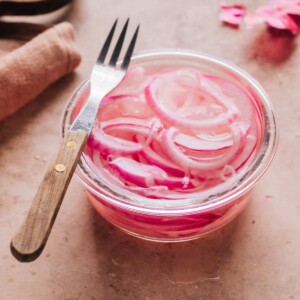 Pickled onion in a glass dish with a fork.