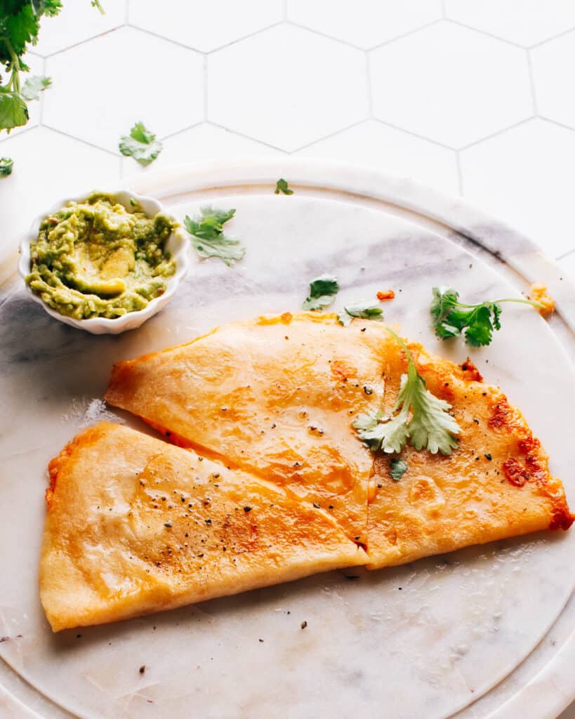 Cheese quesadill aon a plate with guacamole.