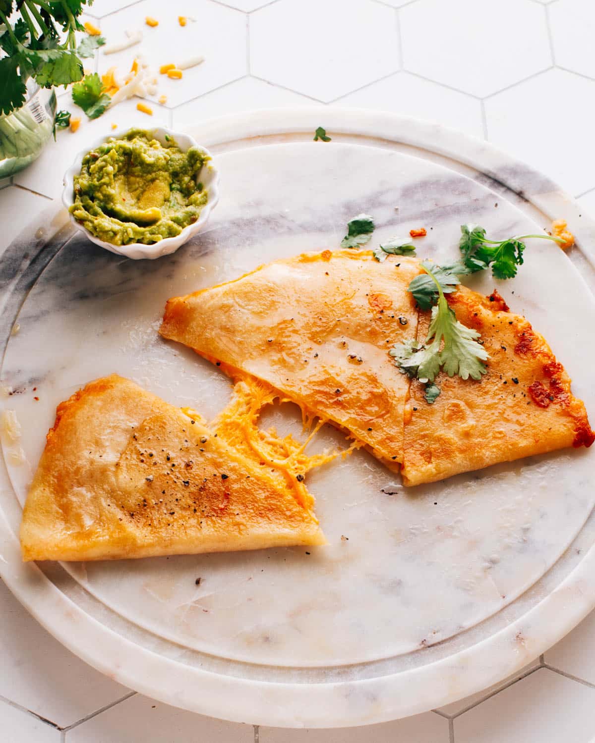 Wedges of cheese quesadillas, accompanied by a small cup of avocado crema.